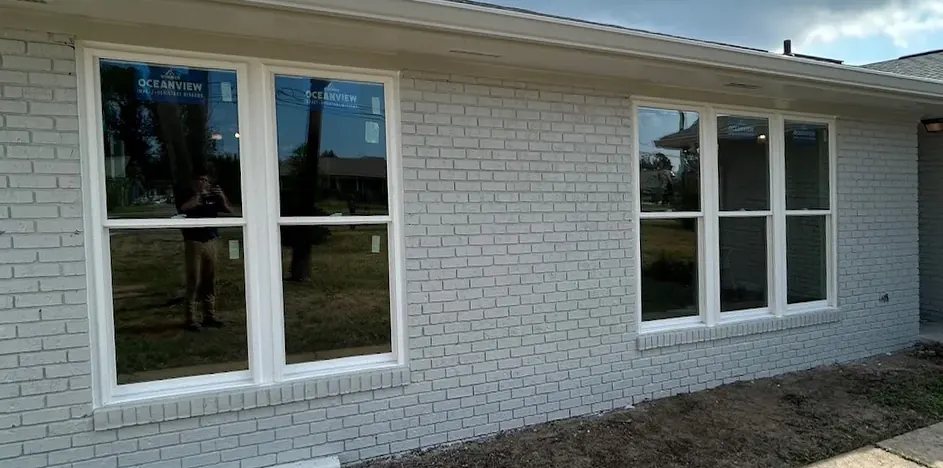 After: the same wall with new white double-hung windows, Oceanview impact-window labels still on the glass.