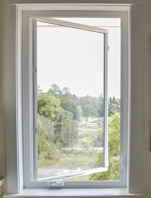 White casement window cranked partly open, looking out at green trees.